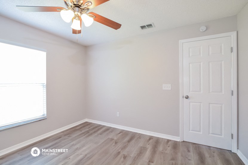 an empty room with a ceiling fan and a window