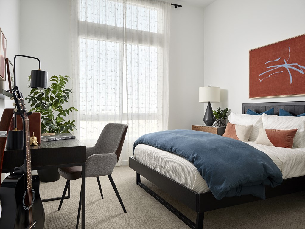 a bedroom with a bed and a guitar and a desk