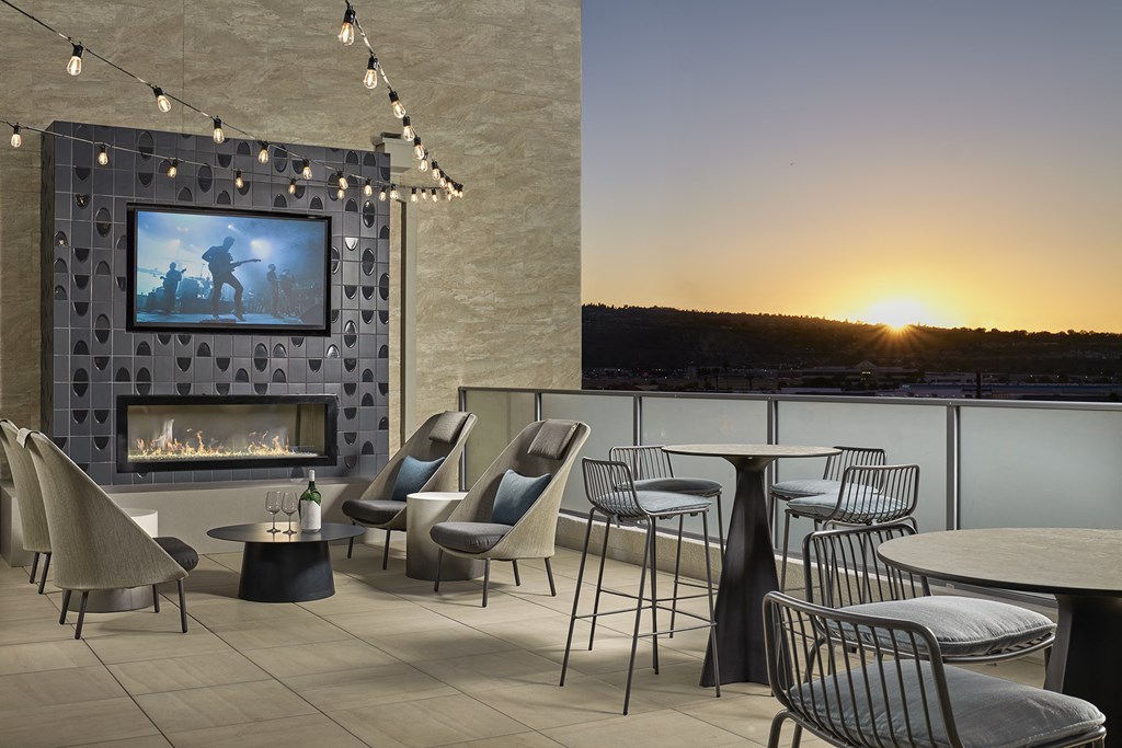 a terrace with tables and chairs and a fireplace and a tv on the wall