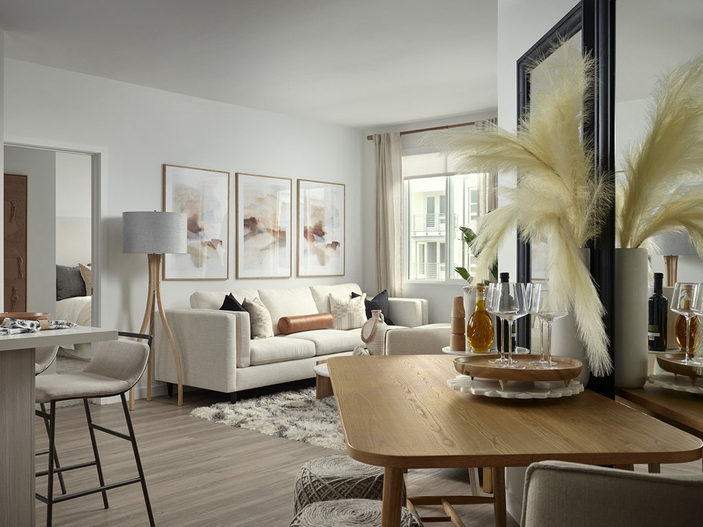 a living room and dining room with white furniture and a wooden table