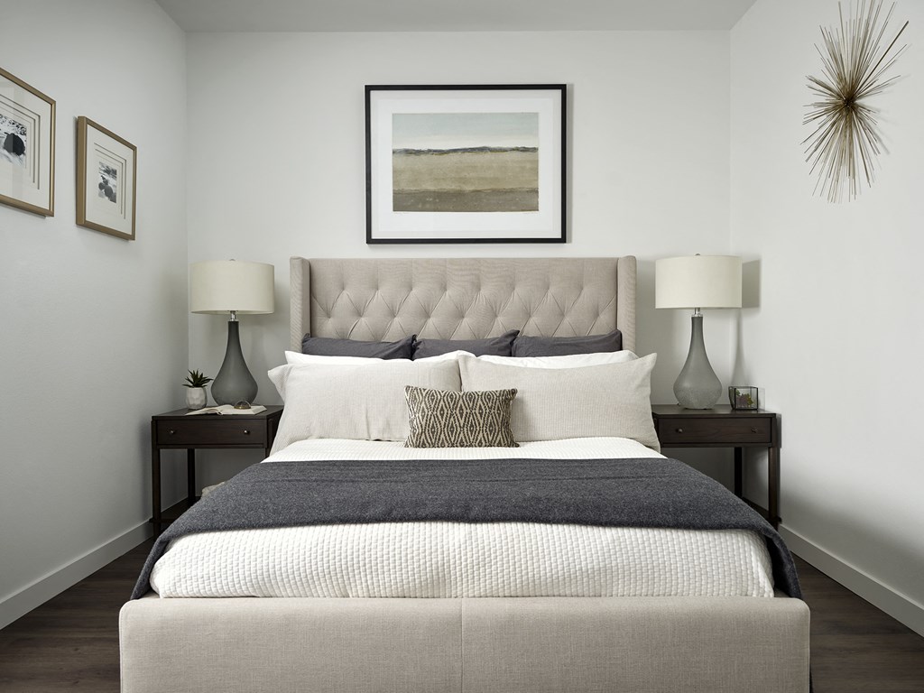 a bedroom with white walls and a bed with a gray blanket and pillows