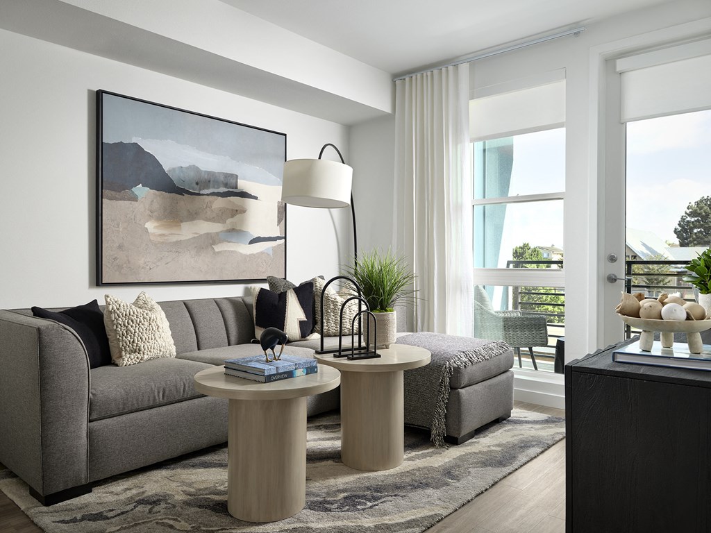 a living room with a gray couch and two round tables