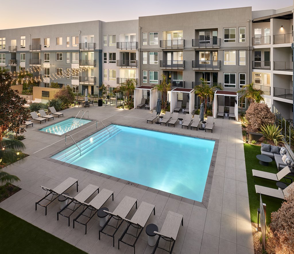 an apartment building with a pool and lounge chairs