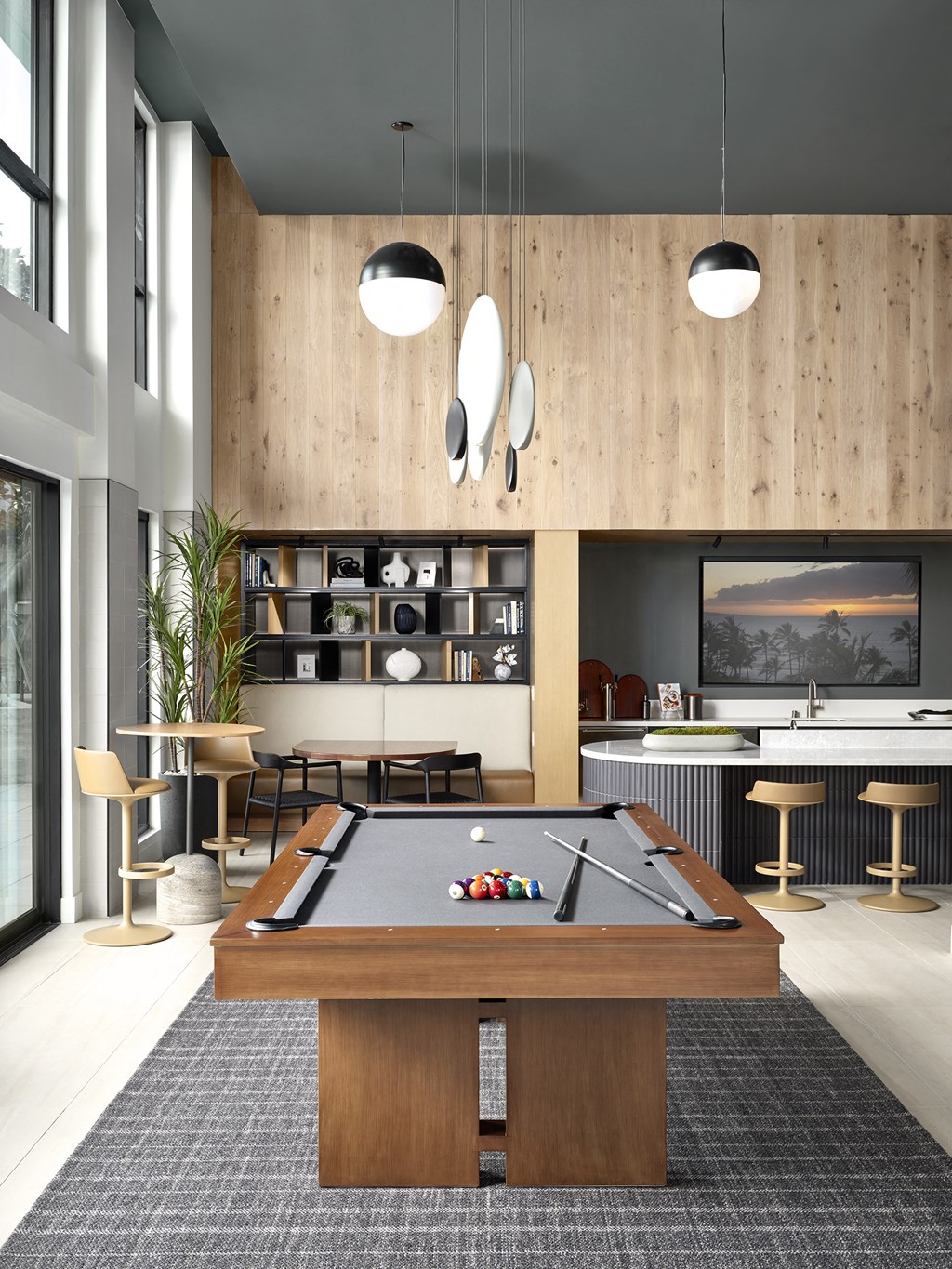 a living room with a pool table and a kitchen with a bar