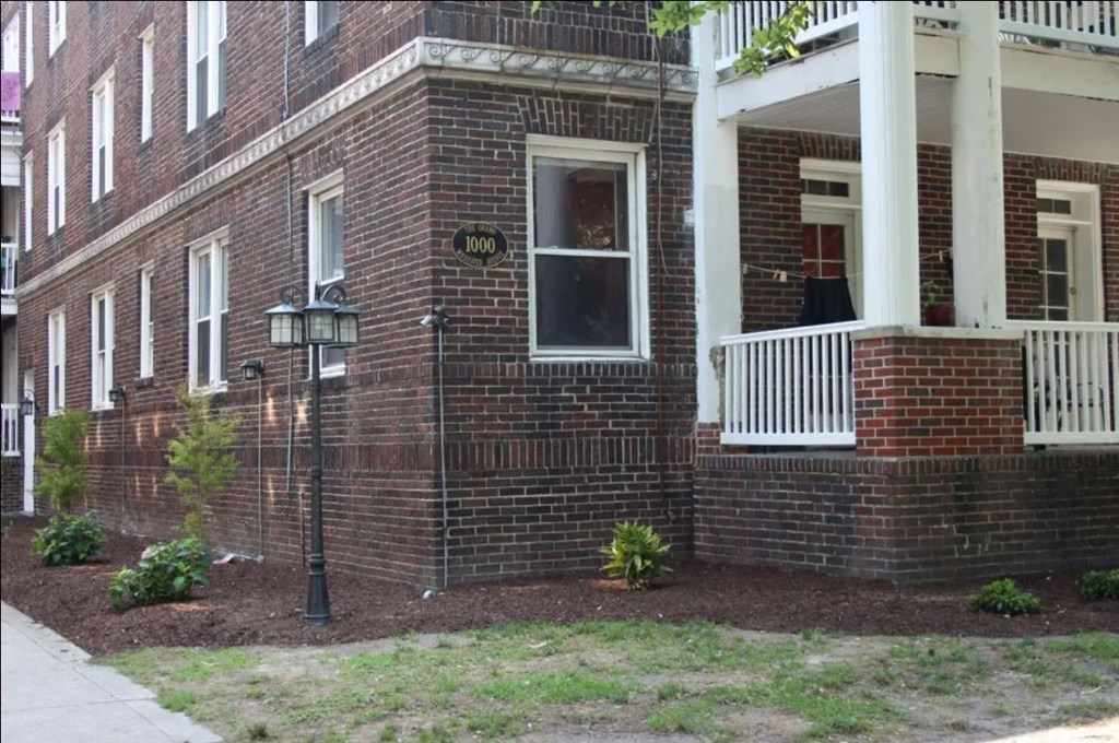 the front of a brick house with a porch and a lamp post