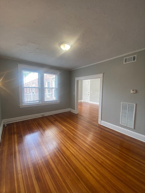 an empty living room with wood floors and a window