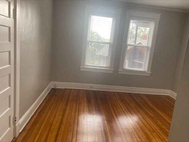 an empty room with wooden floors and two windows
