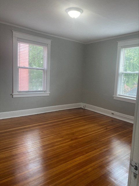 an empty room with a wooden floor and two windows