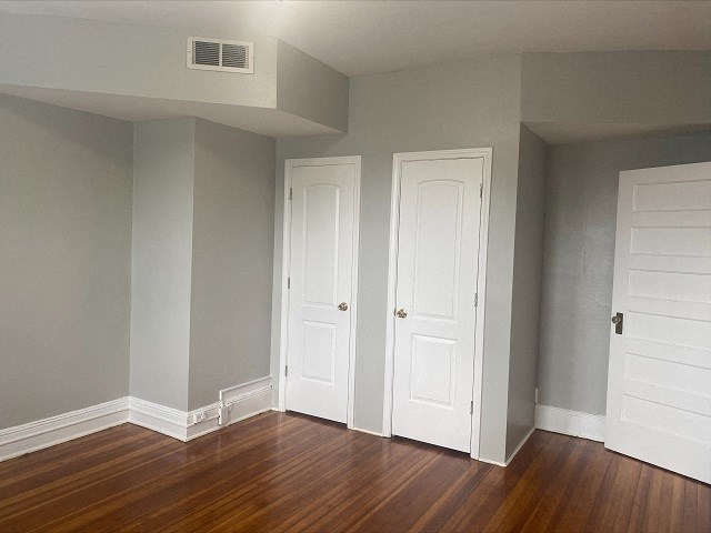 an empty room with two doors and a wood floor