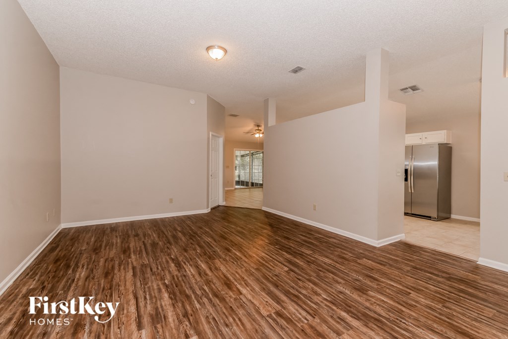the living room and dining room with hardwood flooring and a stainless steel refrigerator