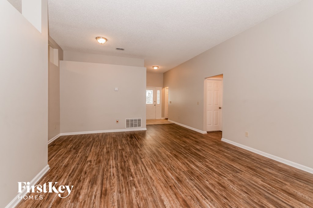 the living room and dining room of an empty house with wood flooring