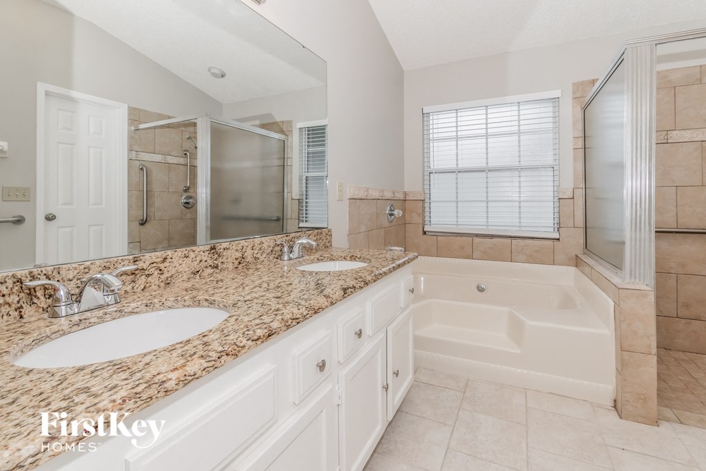 a bathroom with two sinks and a tub and a shower