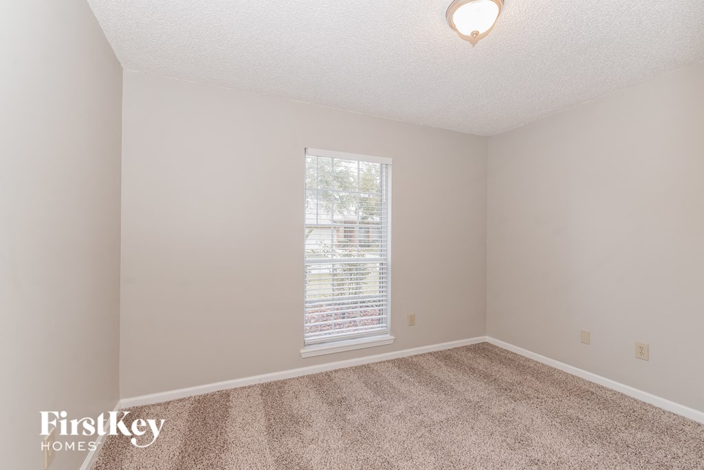 a bedroom with carpet and a large window