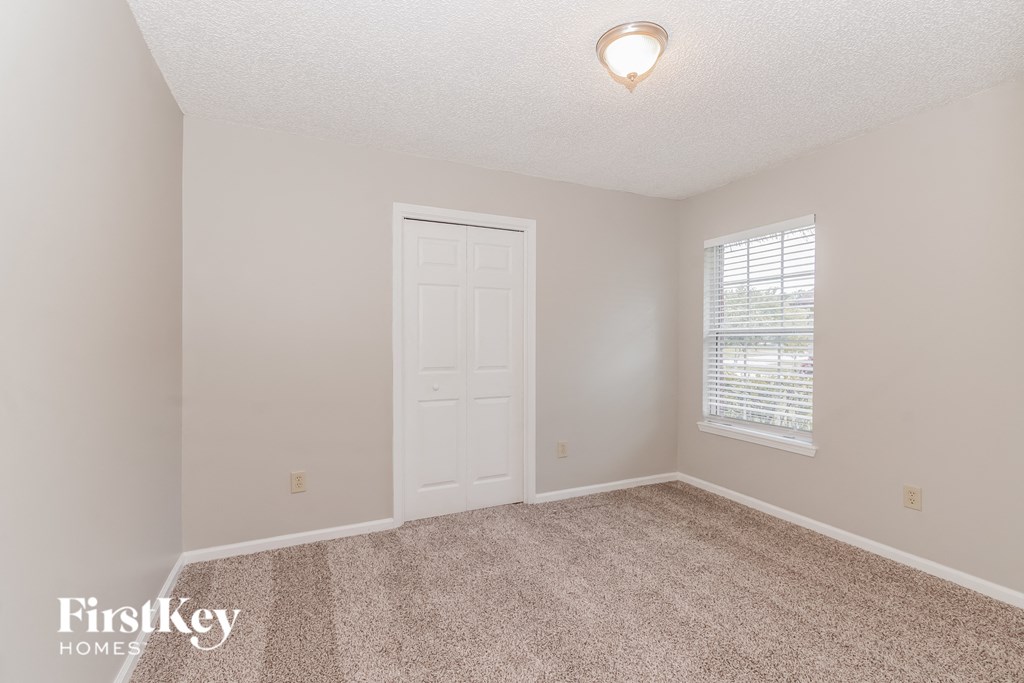 a bedroom with carpet and a white door and window