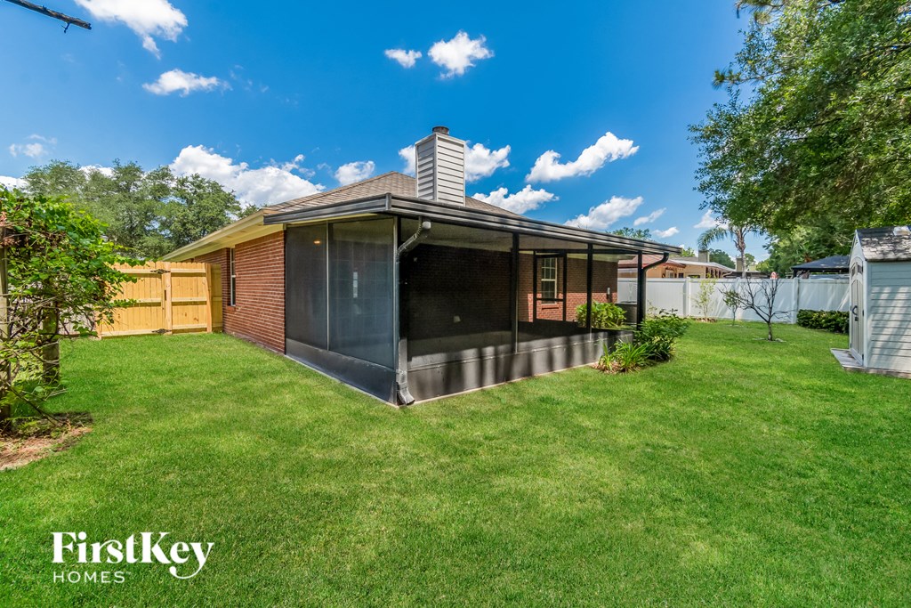 a backyard with a privacy fence and a backyard house with a patio and a lawn