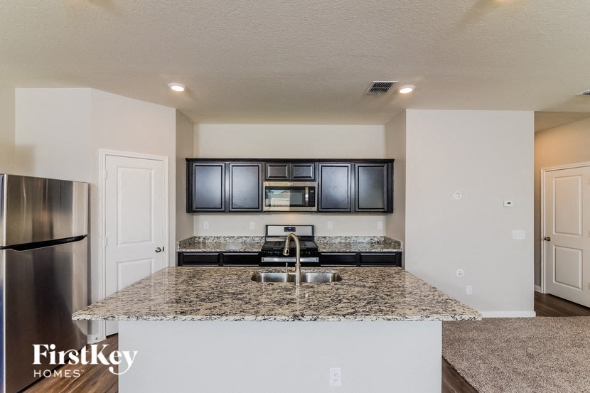 the kitchen has granite counter tops and black cabinets and stainless steel appliances