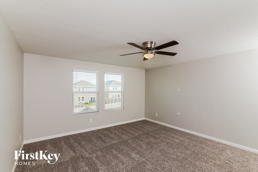 the spacious living room with ceiling fan and carpet