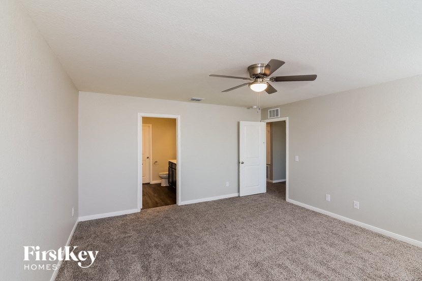 a spacious living room with carpet and a ceiling fan