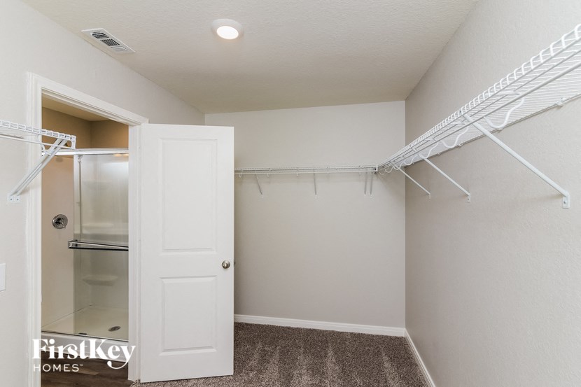 a walk in closet with a white closet door and a mirrored closet