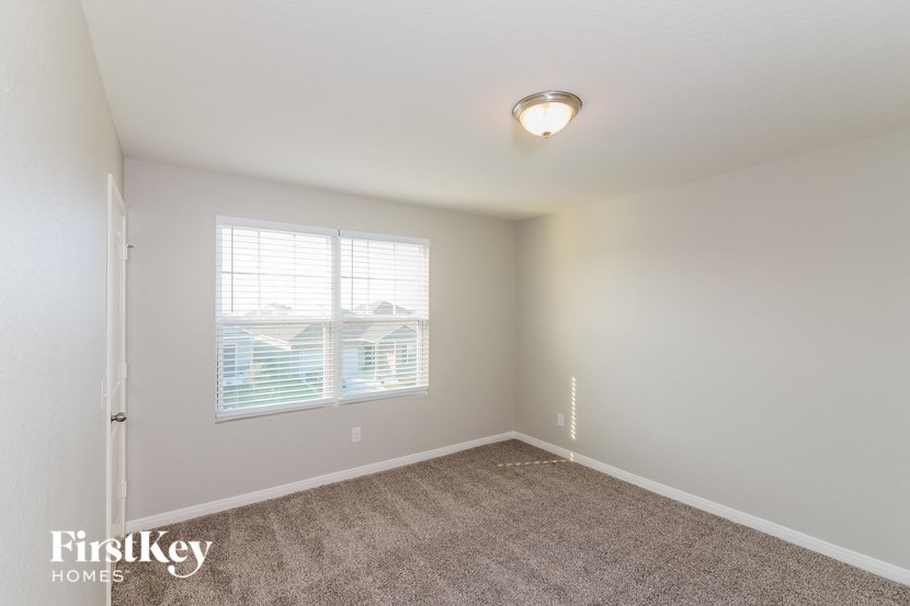 a spacious bedroom with carpeted flooring and a window