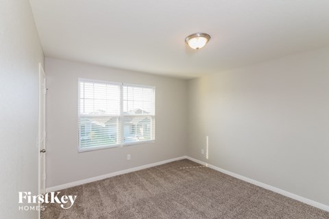 a spacious bedroom with carpeted flooring and a window