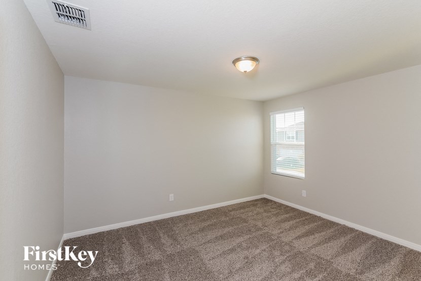 the living room of an apartment with carpet and a window
