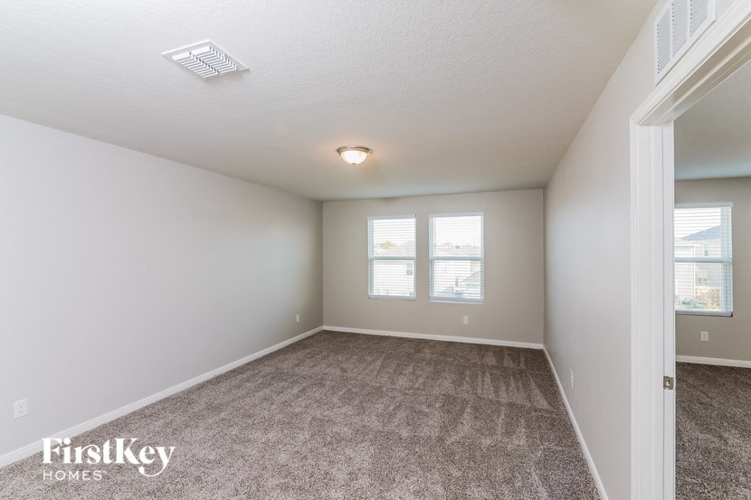 a spacious living room with carpet and two windows