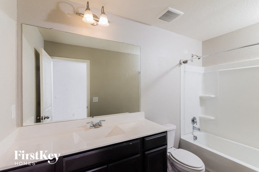 a white bathroom with a large mirror and a white tub and sink