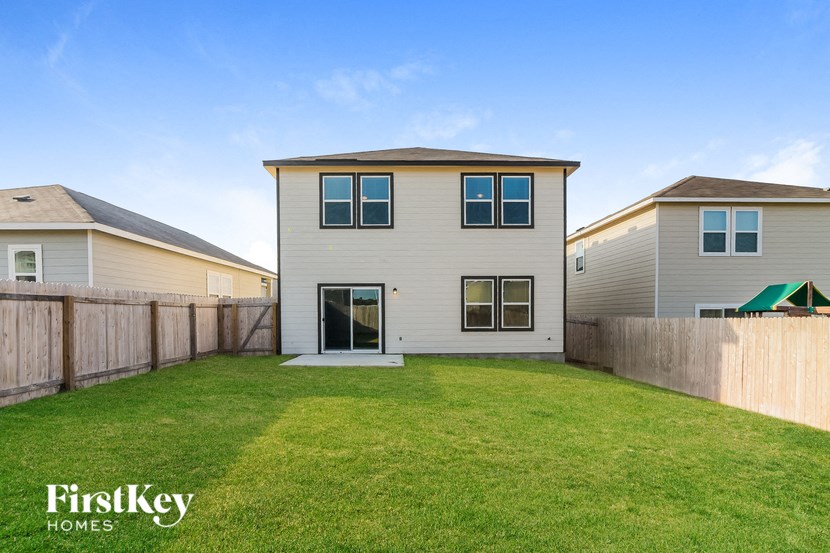 a backyard with a white house and a fence