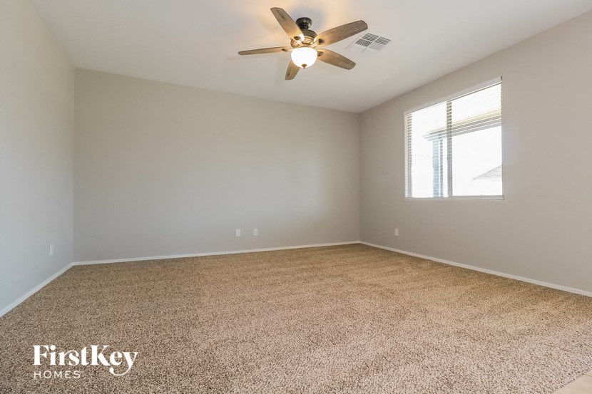 an empty living room with a ceiling fan and a window
