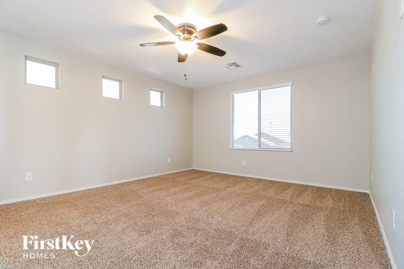 an empty living room with a ceiling fan and a window