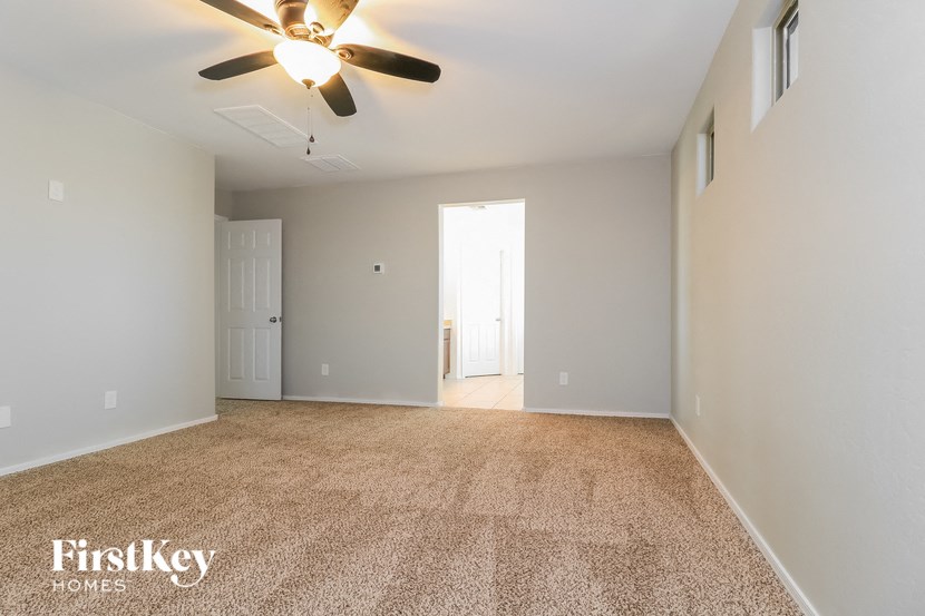 an empty living room with a ceiling fan and white walls
