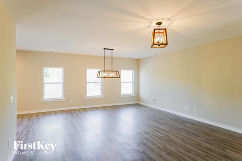 A large empty room with wooden floors and a hanging light fixture.