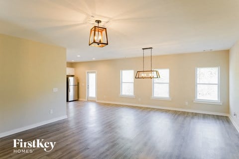 A spacious room with wooden floors and a hanging light fixture.
