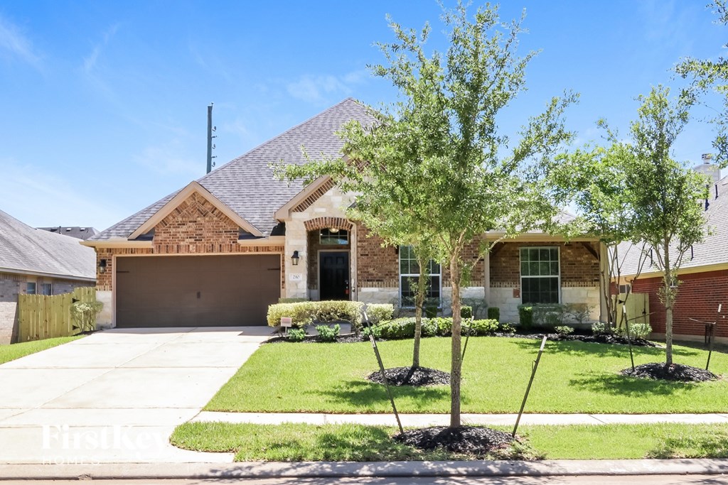 A house with a garage and a driveway with a tree in front.