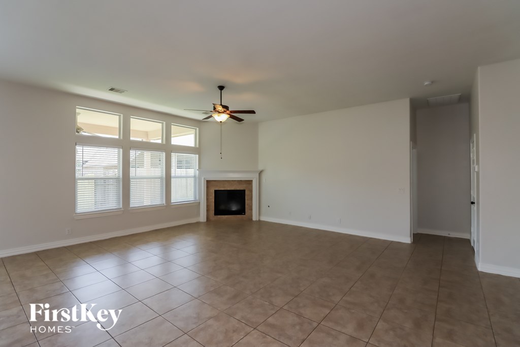 A spacious room with a fireplace and a ceiling fan.