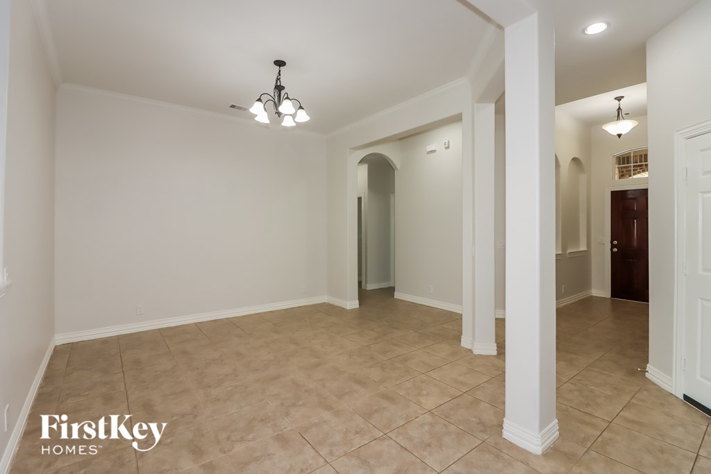 A spacious room with a tiled floor and a chandelier hanging from the ceiling.
