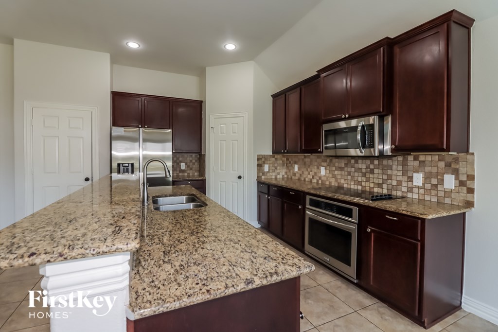A kitchen with granite countertops and brown cabinets.