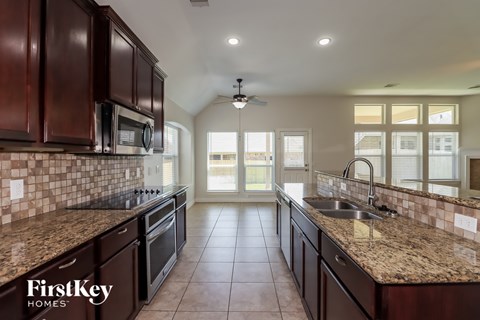 A kitchen with brown cabinets and a tile floor.