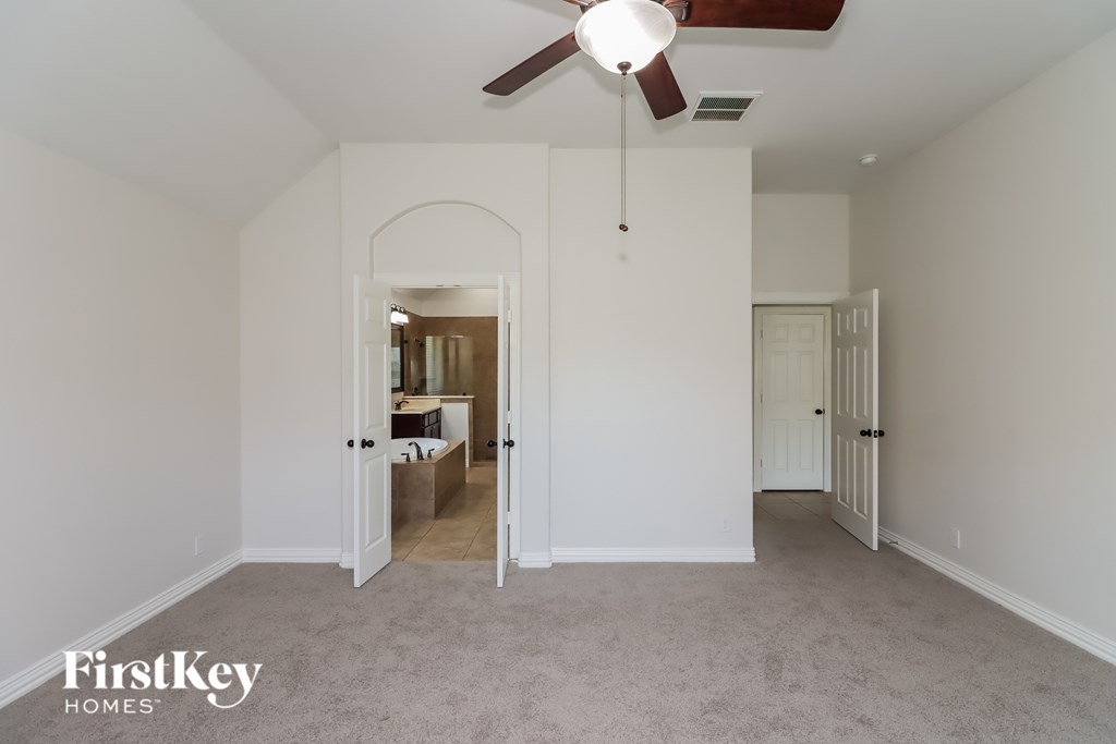 A spacious room with a ceiling fan and a carpeted floor.
