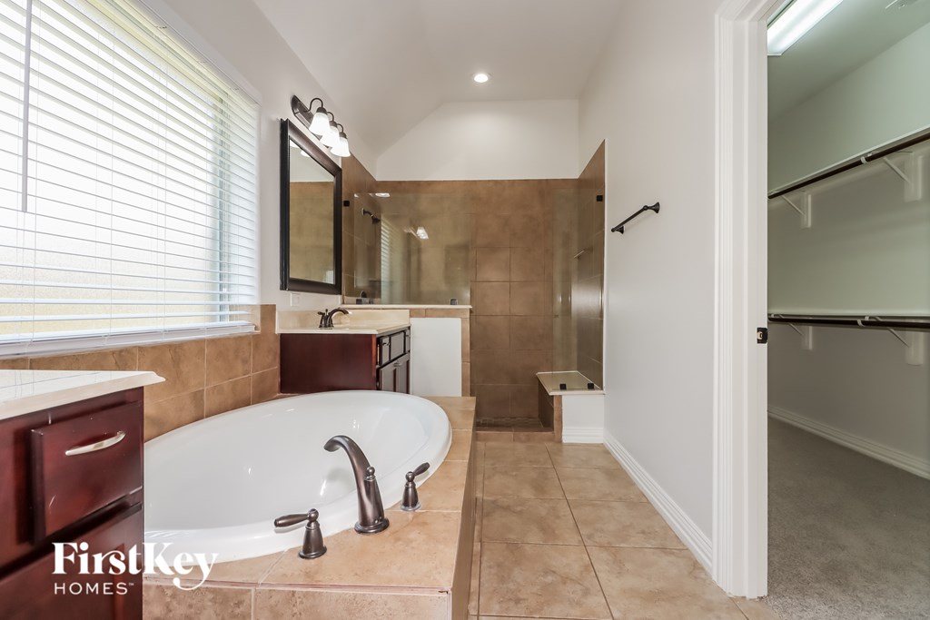 A bathroom with a tub, sink, and mirror.