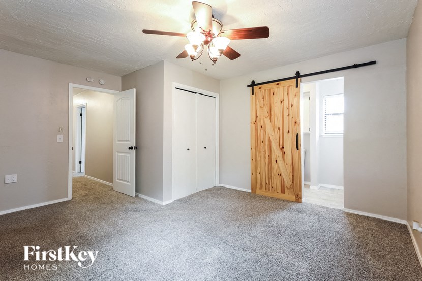 the master bedroom has a barn door closet and carpeted flooring
