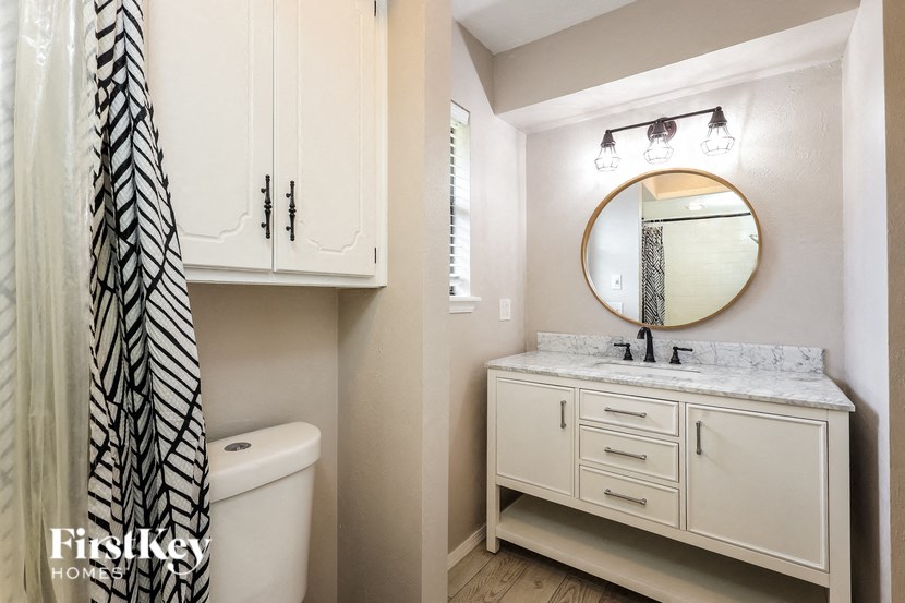 a bathroom with white cabinets and a white sink and toilet