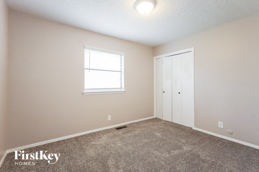 a bedroom with a carpeted floor and a door to a closet
