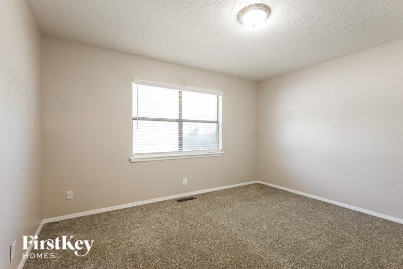 a bedroom with a window and a carpeted floor