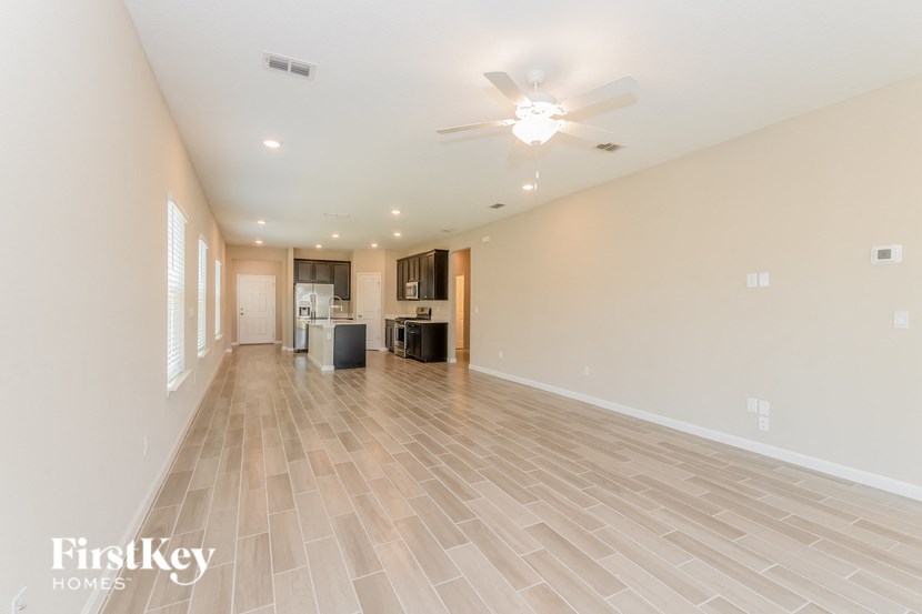 A spacious room with wooden flooring and a ceiling fan.