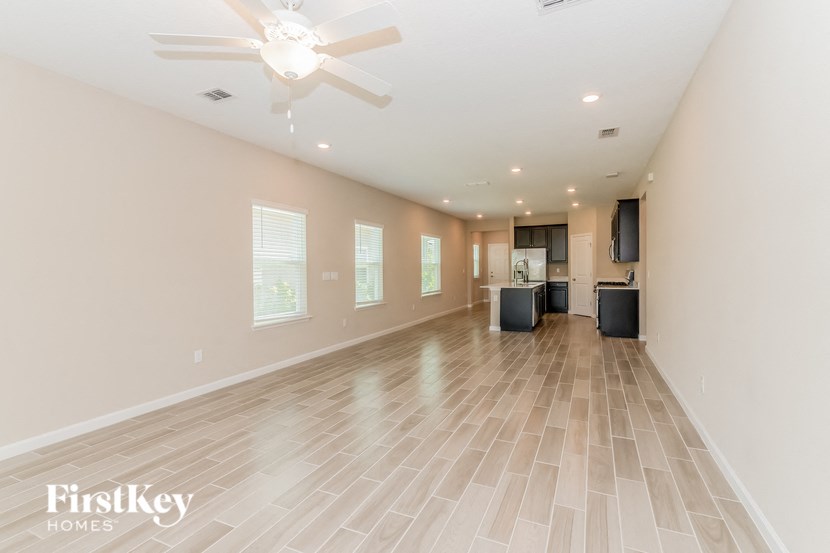 A spacious room with a ceiling fan and lighting fixtures.
