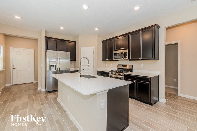 A kitchen with a white island and black cabinets.