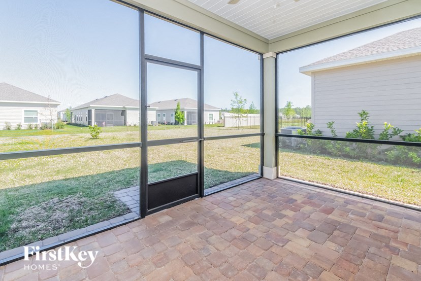 A patio with a sliding glass door and brick flooring.