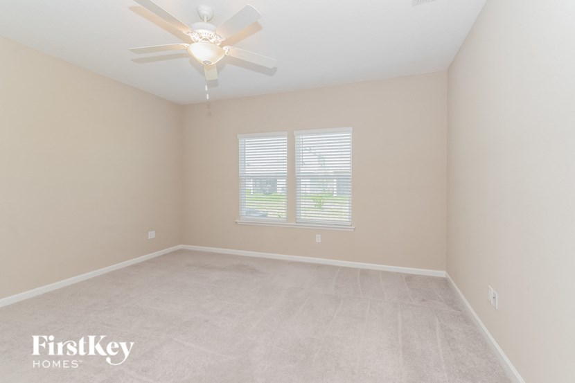 A room with a ceiling fan and a window with blinds.
